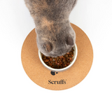 A cat eating kibble from a bowl on a Scruffs Cork Placemat for pets with a paw print design.