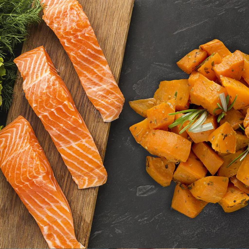 Salmon and sweet potato on a slate and wooden surface.