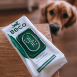 A retriever dog looking up at a packet of Beco Coconut scented bamboo wipes.