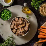 Bowl of Forthglade whole grain wet food surrounded by raw ingredients including carrots and peas.