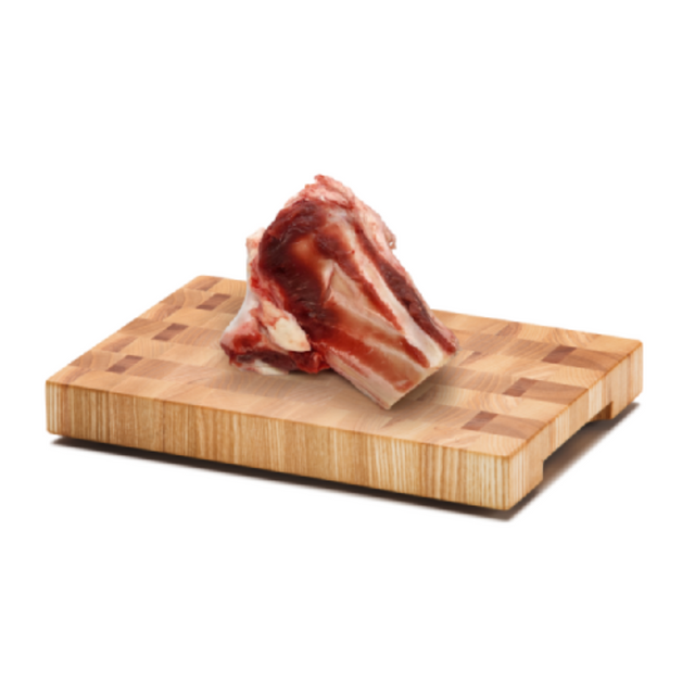 Naked dog raw beef knuckle bone on a wooden chopping board.