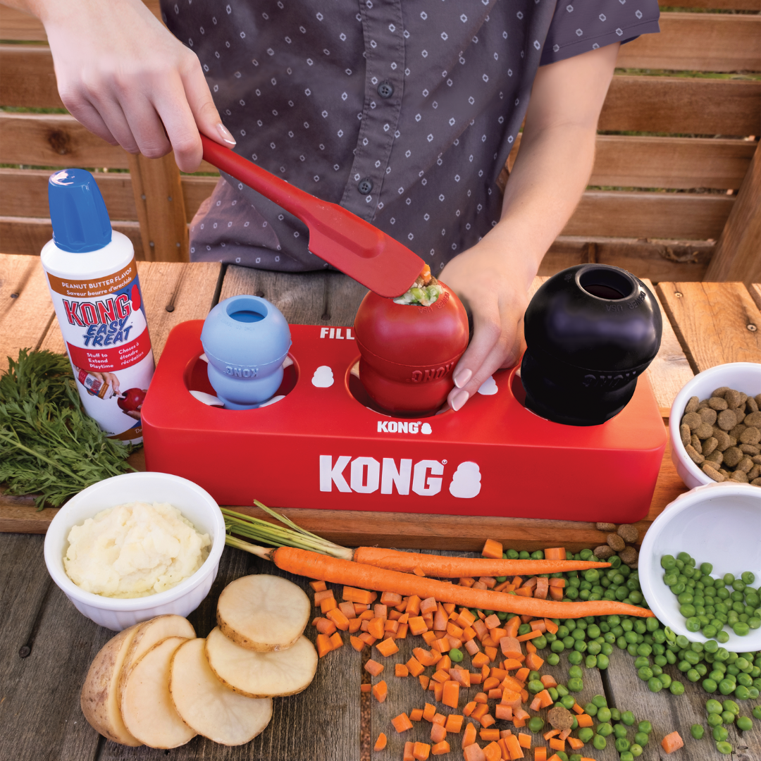 A person filling up a variety of  ingredients. Table has fresh vegetables on it.