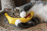 Tabby and white cat with a Yeowww Catnip banana between its front paws